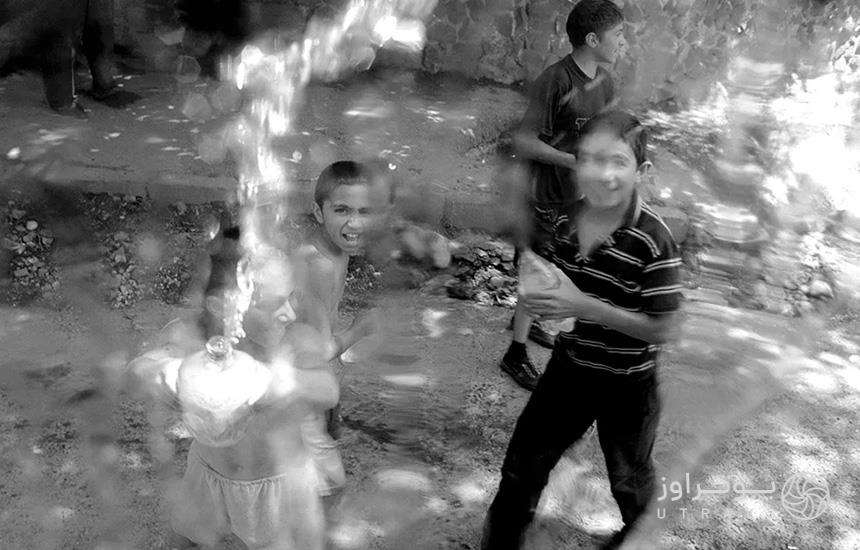 عکسی سیاه‌وسفید از چند پسربچه درحال آب پاشیدن به سمت دوربین عکاس